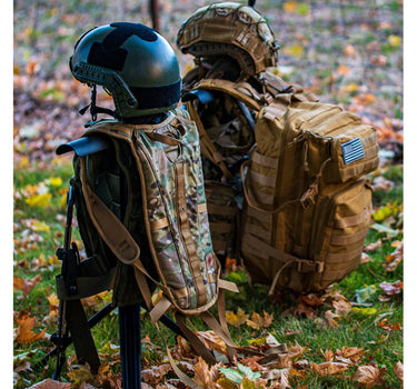 Wobig Portable Tactical Gear Stand with a sleek black finish, featuring a central pole and a horizontal crossbar, set up on a grassy lawn with a backdrop of fallen autumn leaves